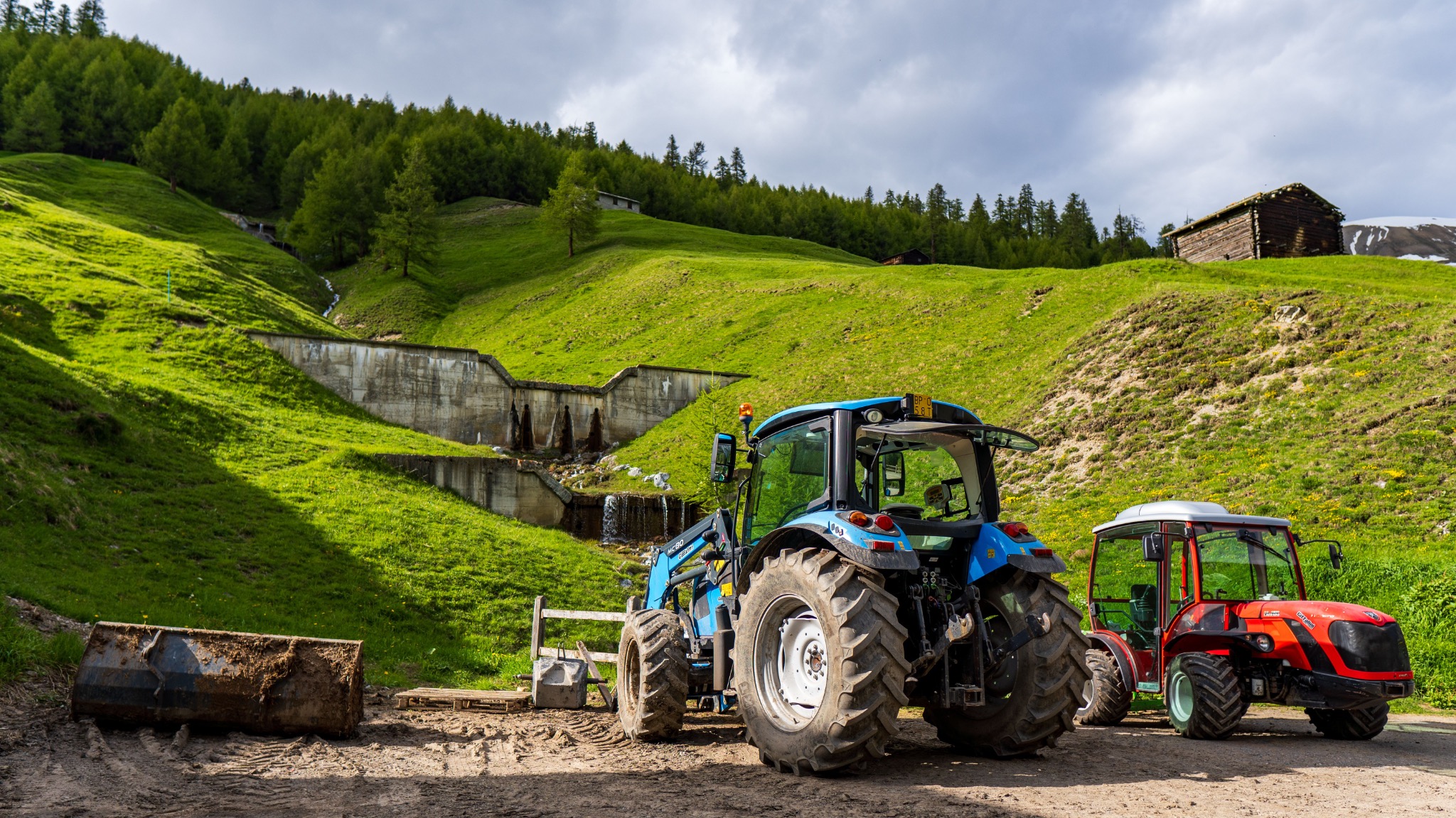 Dois tratores agrícolas numa paisagem verde de montanha